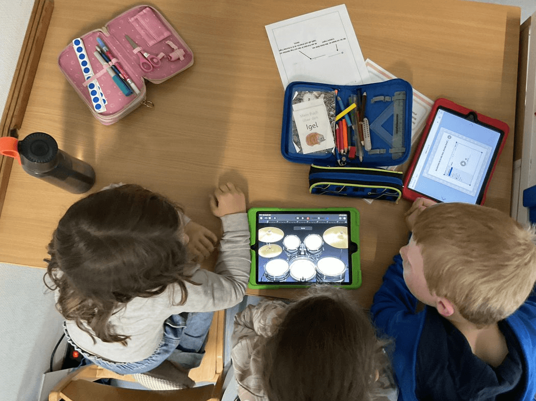 Kinder arbeiten gemeinsam an einem iPad (von oben, nicht erkennbar)